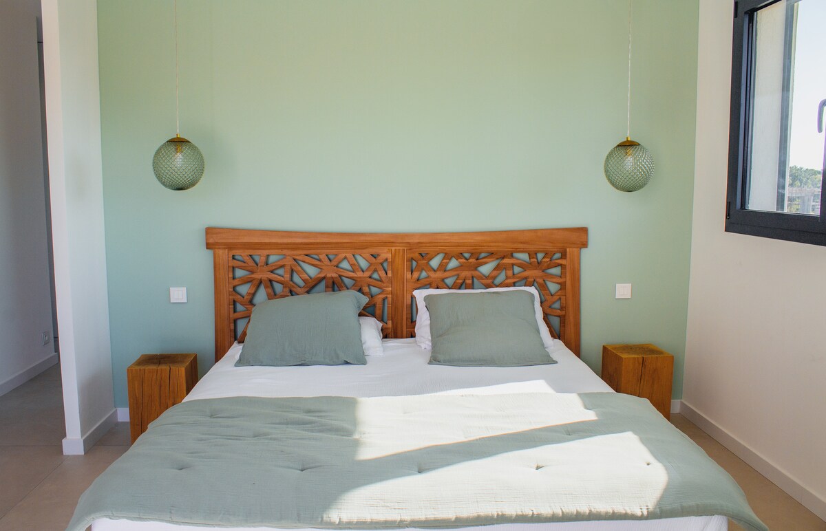 Chambre claire avec lit double et tete de lit coloree.