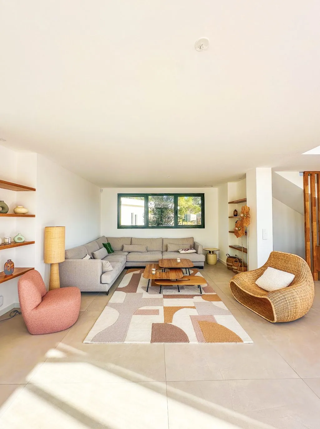 Salon avec canape, fauteuils en rotin et etageres murales.